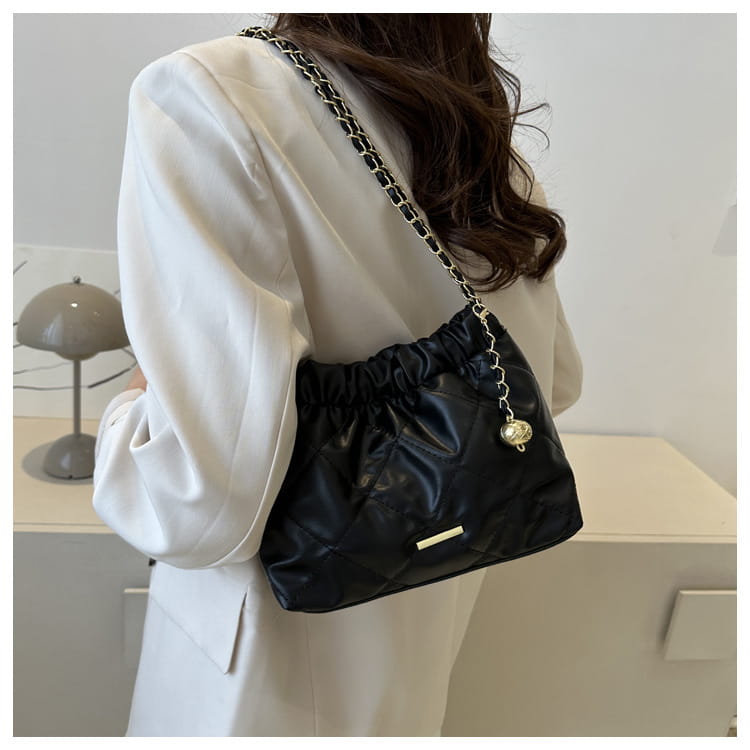 Black quilted faux leather crossbody bag with a chain strap and gold-tone hardware designed for shoulder wear.