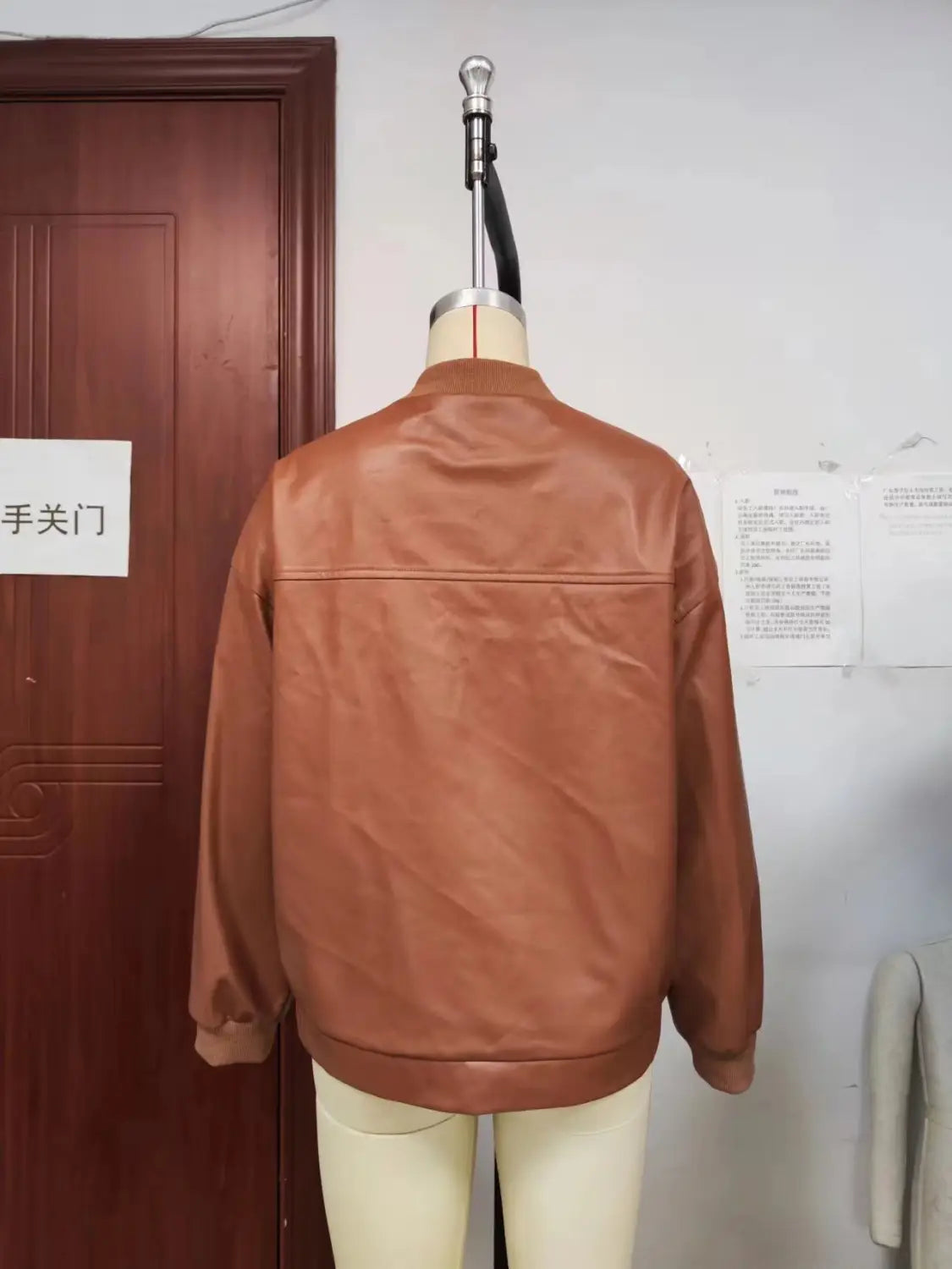 A tan faux leather bomber jacket with a classic collar seam detailing and ribbed cuffs.