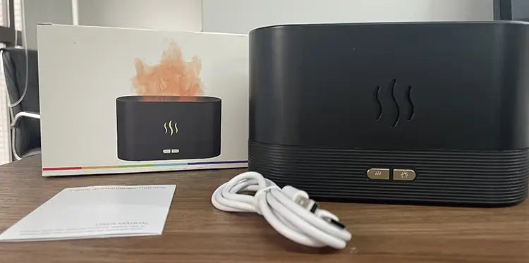 Black cylindrical flame humidifier rgb essential oil aroma diffuser with a textured surface and gold-colored control buttons with 180ml capacity.