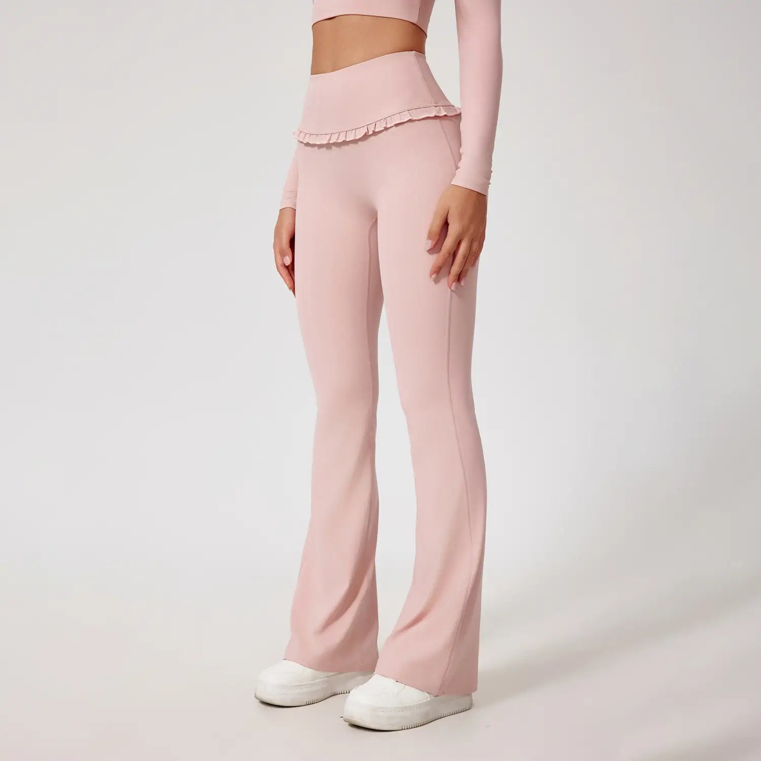 Leggings roses taille haute évasés en tissu extensible, avec ourlet volanté, adaptés à la tenue active.