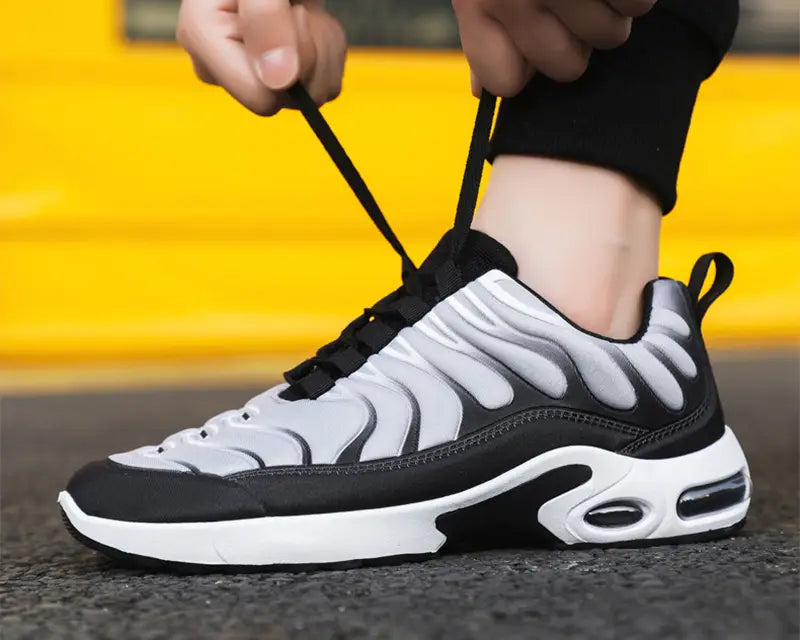 Black and white air cushion running shoes featuring a flame pattern fashion sneaker with a distinctive wave-like upper design and an air cushioned sole.