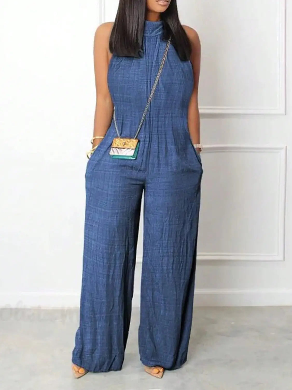Blue denim jumpsuit with a high neckline and wide-leg design in a halter style.