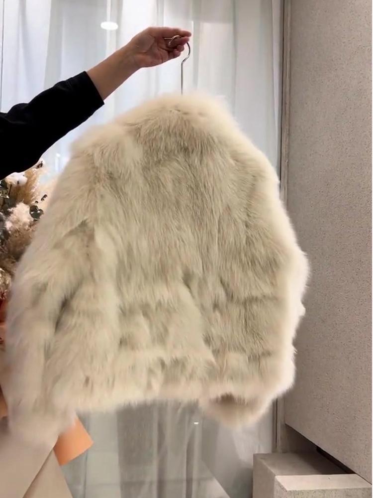 A plush off-white faux fur cream buckle coat with soft voluminous texture and long flowing strands.