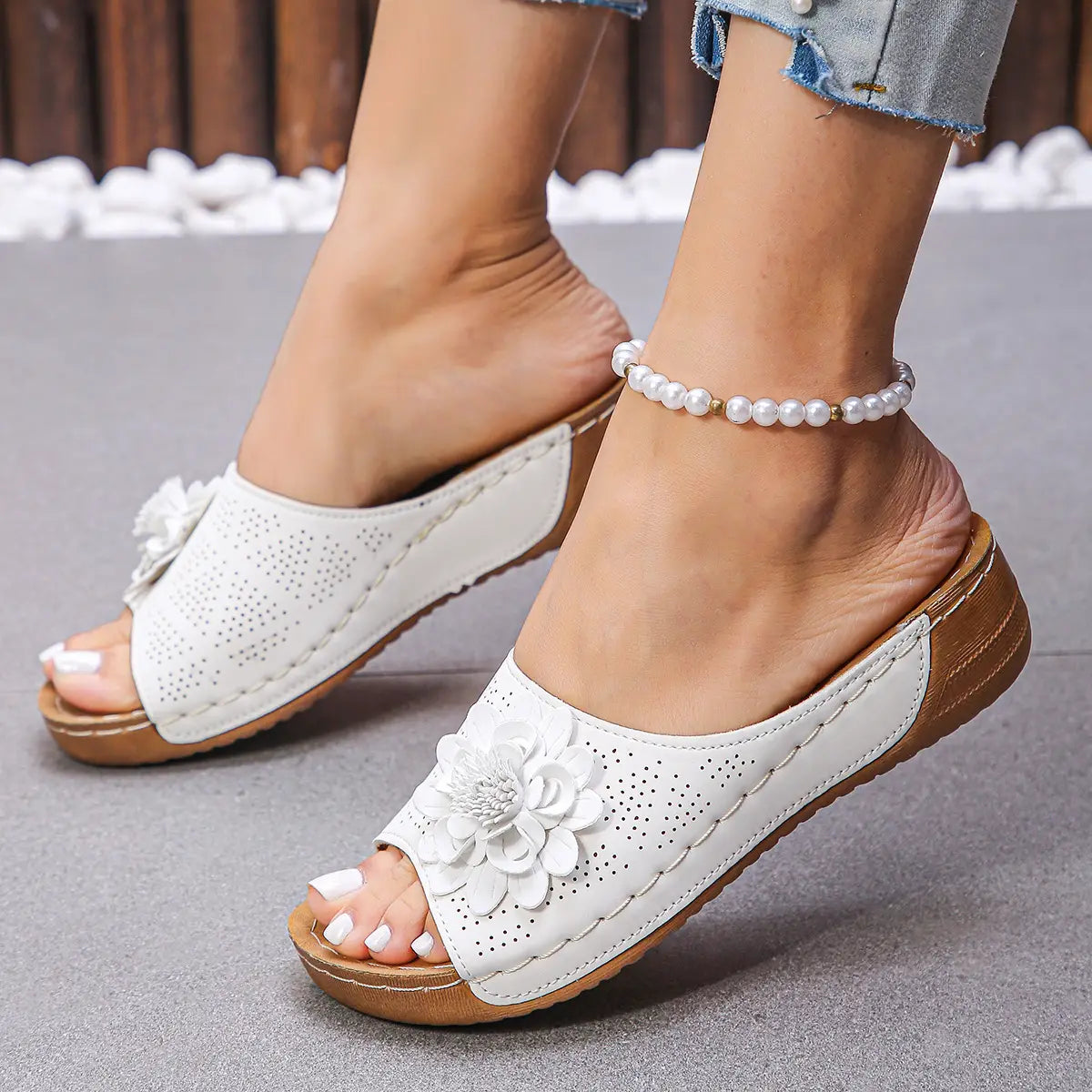 Sandalias tipo bandolera de cuero blanco con un diseño perforado y un gran adorno floral, destacadas en sandalias de cuña de flores estilo hollow de cuero retro para la playa.