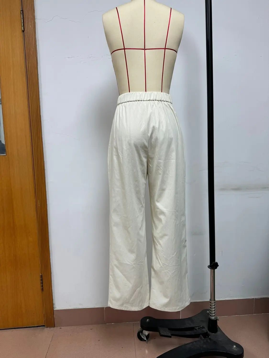 Pantalons blancs à jambes larges avec des plis à la taille haute et une ceinture élastique, présentés sur un mannequin