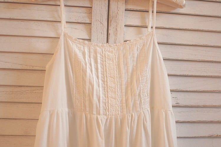 Ein zartes cremefarbenes Baumwoll-Spitzenkleid mit Volants (gestufter Rock) mit dünnen Spaghettiträgern und aufwendigen Spitzen-Details entlang des Vorderpaneels.