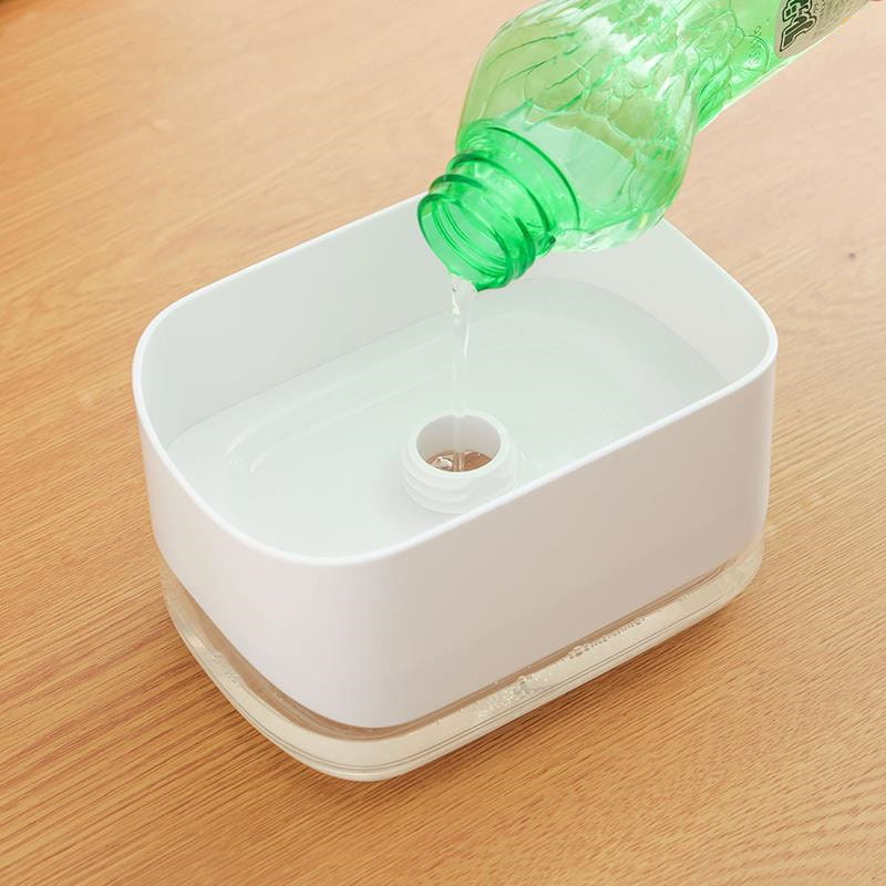 Dispensador rectangular de jabón líquido para platos blanco con base de vidrio transparente y entrada central de agua, que incorpora un soporte para esponja, capacidad de 350 ml.