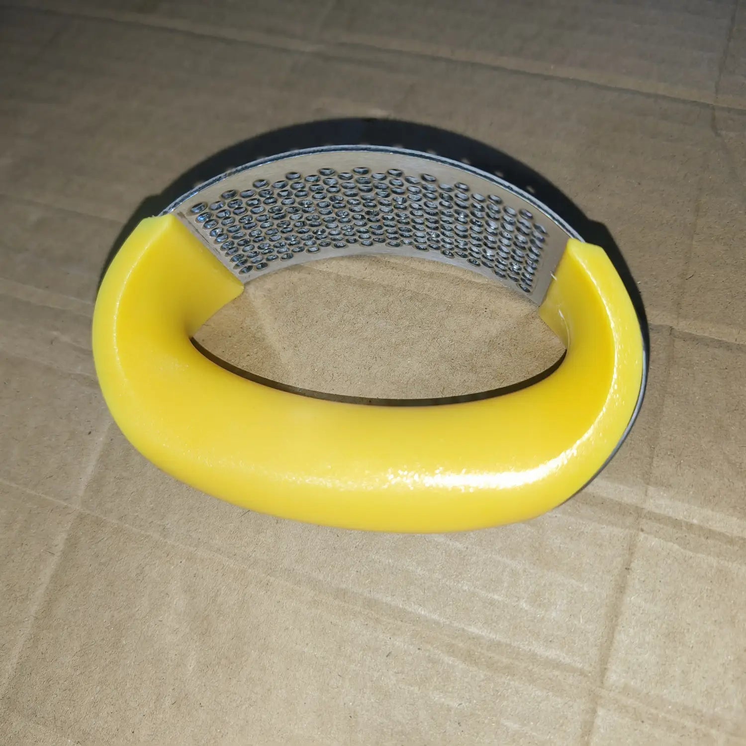 Râpe de cuisine à poignée jaune, surface métallique texturée et poignée noire recouverte de caoutchouc pour un hachage manuel ergonomique dans un outil de presse-ail en acier inoxydable