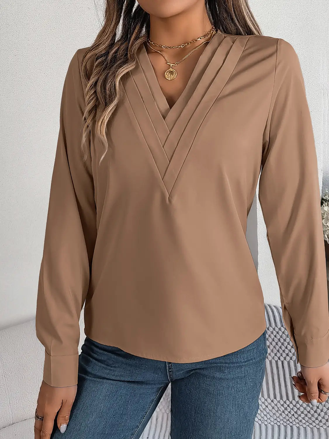 beige long-sleeved blouse with v-neckline and subtle pleats designed as a white satin v neck wrap blouse with black trim