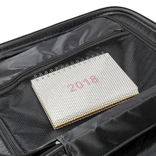 black mesh-lined compartment inside a blue textured rolling hardshell suitcase holds a white spiral-bound notebook with red lettering in the 3-in-1 suitcase set
