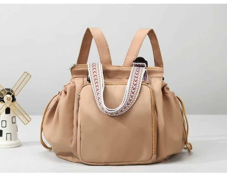 Beige multifunctional waterproof nylon fashion tote and backpack featuring a braided white and red strap.