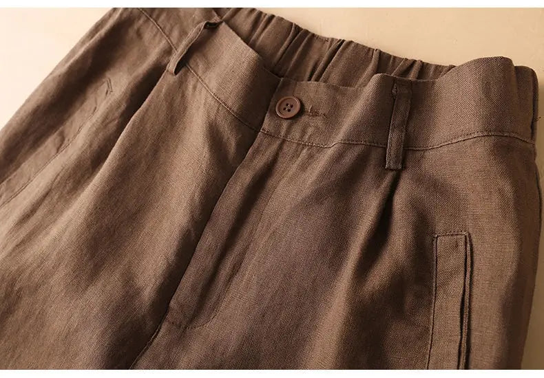 ブラウンのコットンリネン素材クロップドパンツ（3/4丈）。ハイウエストでリラックスしたフィット、伸縮性ウエストバンド、シングルボタンの留め具を備えたカジュアルトラウザー。