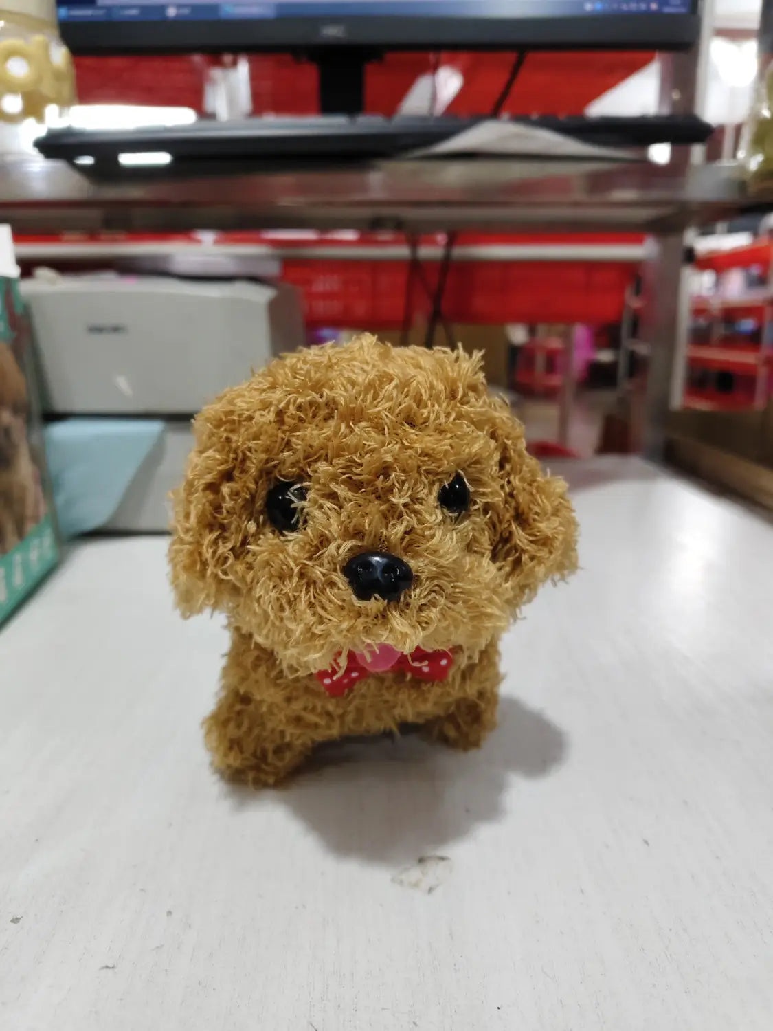 A fluffy tan interactive plush robot puppy with black button eyes and a red polka-dot bow tie featuring sound and music capabilities.