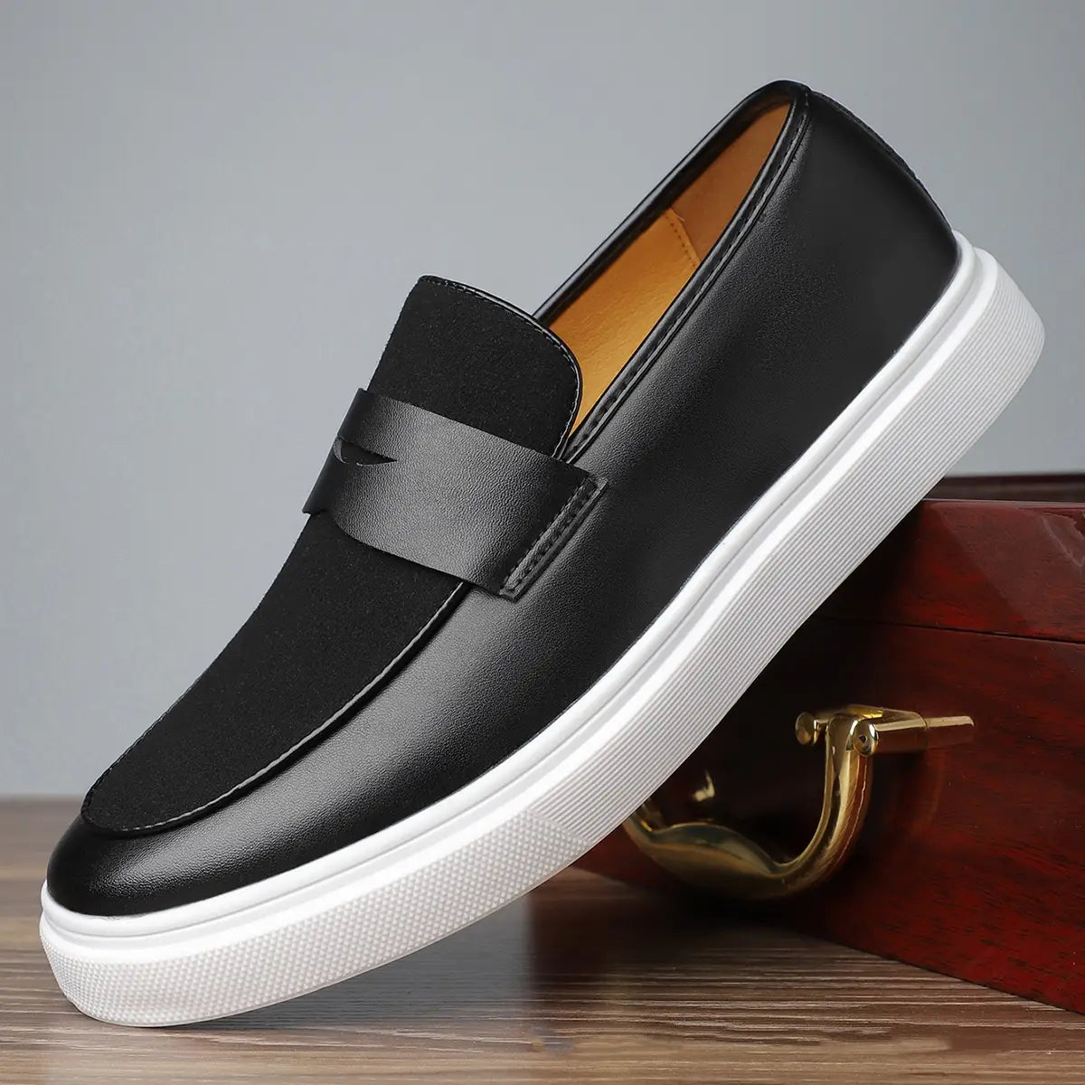 Herren-Leder-Slipper zum Hineinschlüpfen in Schwarz mit weißer Gummisohle und einem minimalistischen Riemen über dem Vorderblatt.