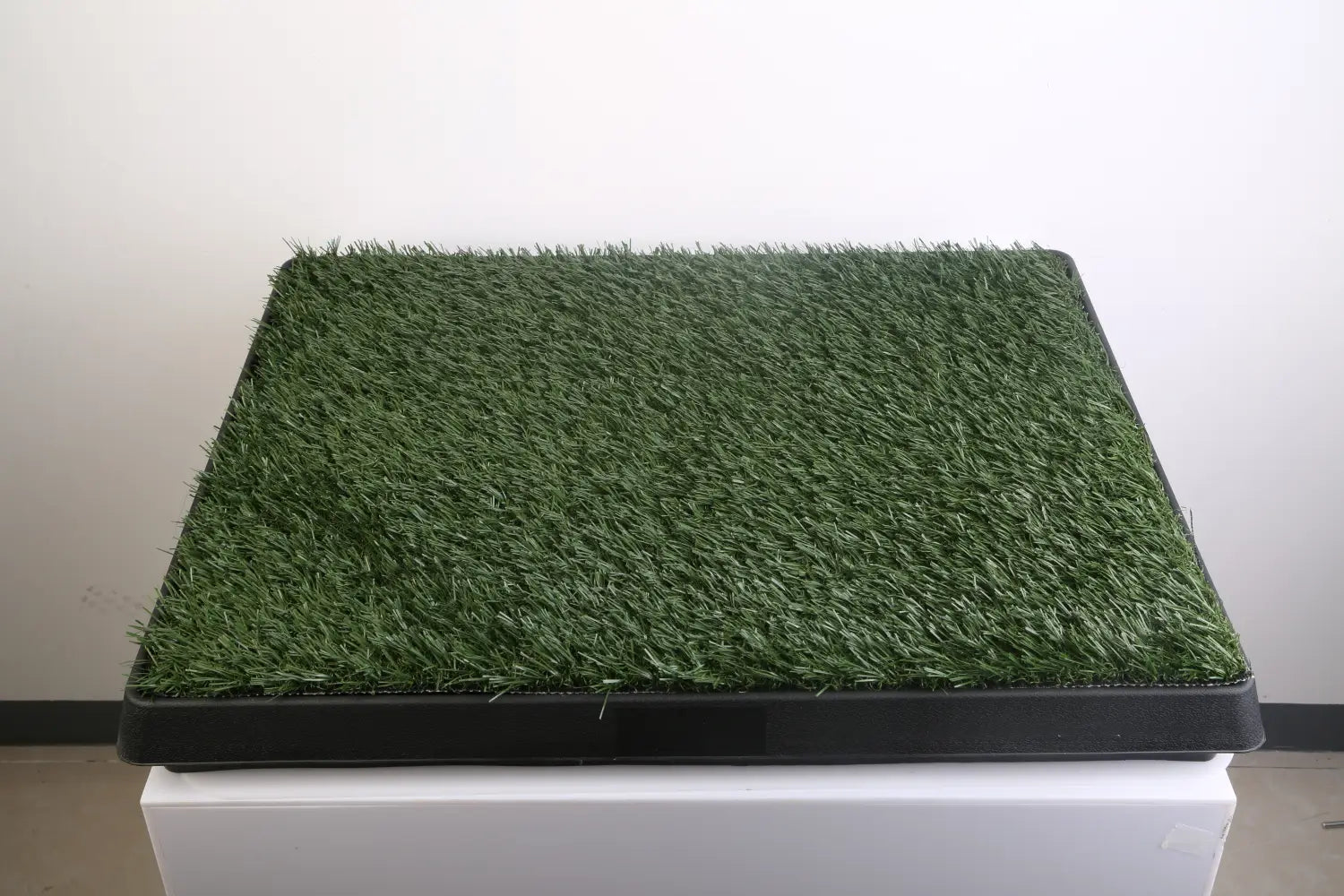 green artificial grass mat with a black plastic base for dog potty training artificial grass mat tray shown from the back side