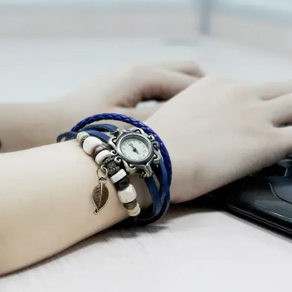 bohemian blue braided leather leaf charm wrap watch with a silver-toned ornate case white face and alternating cream and dark beads with a small leaf charm