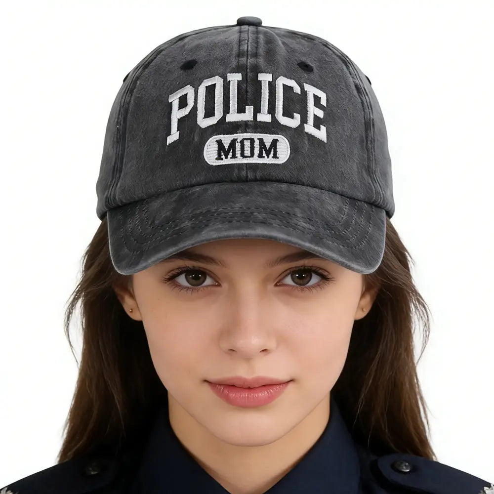 Una gorra de béisbol de algodón con aspecto desgastado en color gris oscuro, con "police mom" bordado en blanco con letras en arco encima de un parche rectangular.