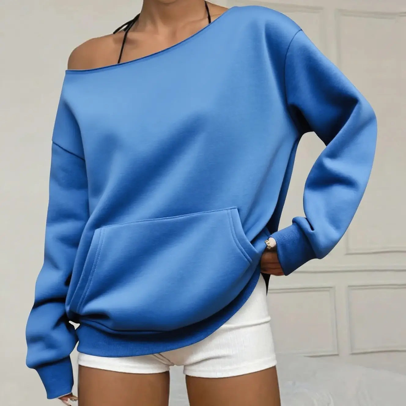 Ein leuchtend blauer, oversized schulterfreier Pullover mit Fronttasche und gerippten Bündchen, ideal für den Alltag.