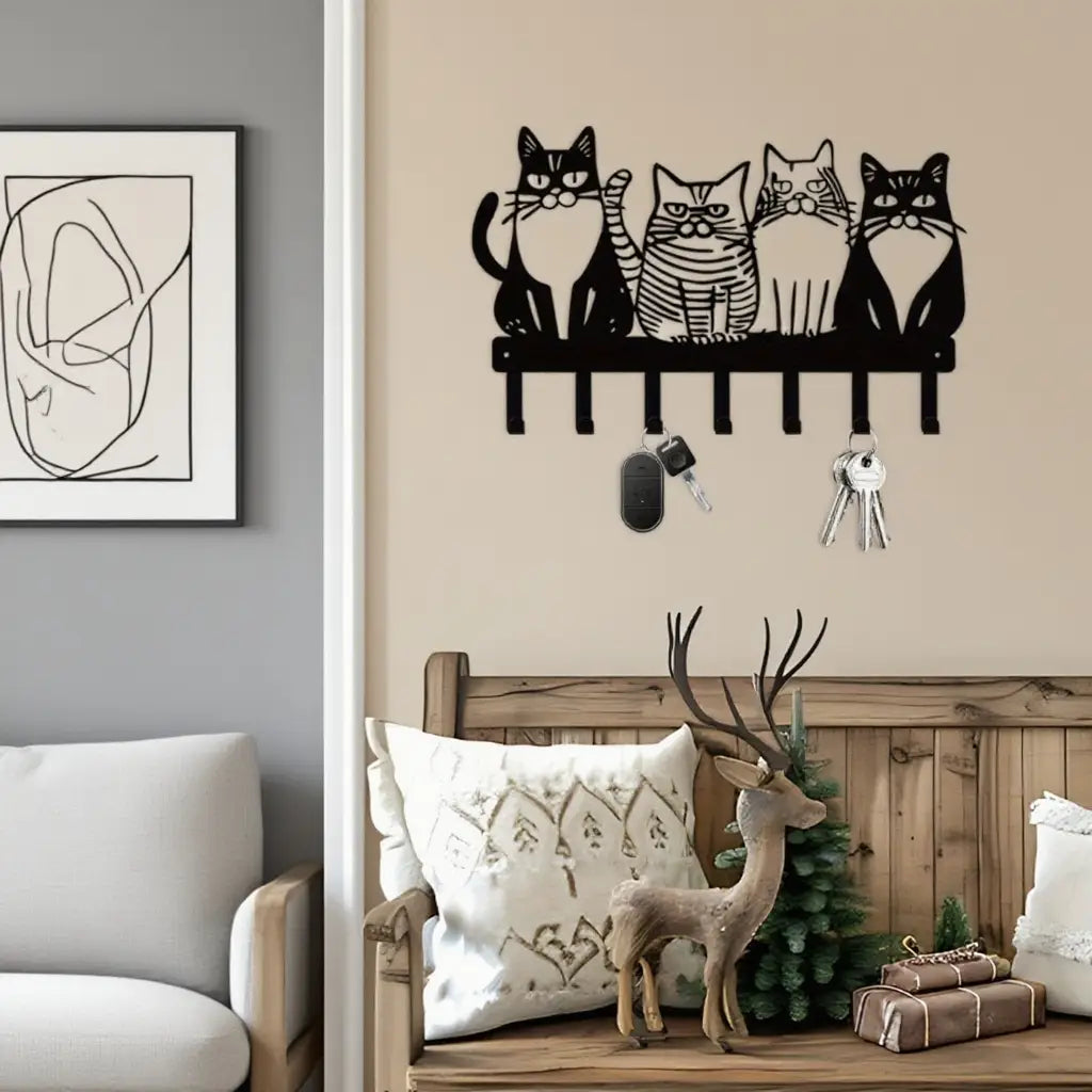 Black metal wall-mounted cat key holder with four stylized feline figures and four hooks for home decor.