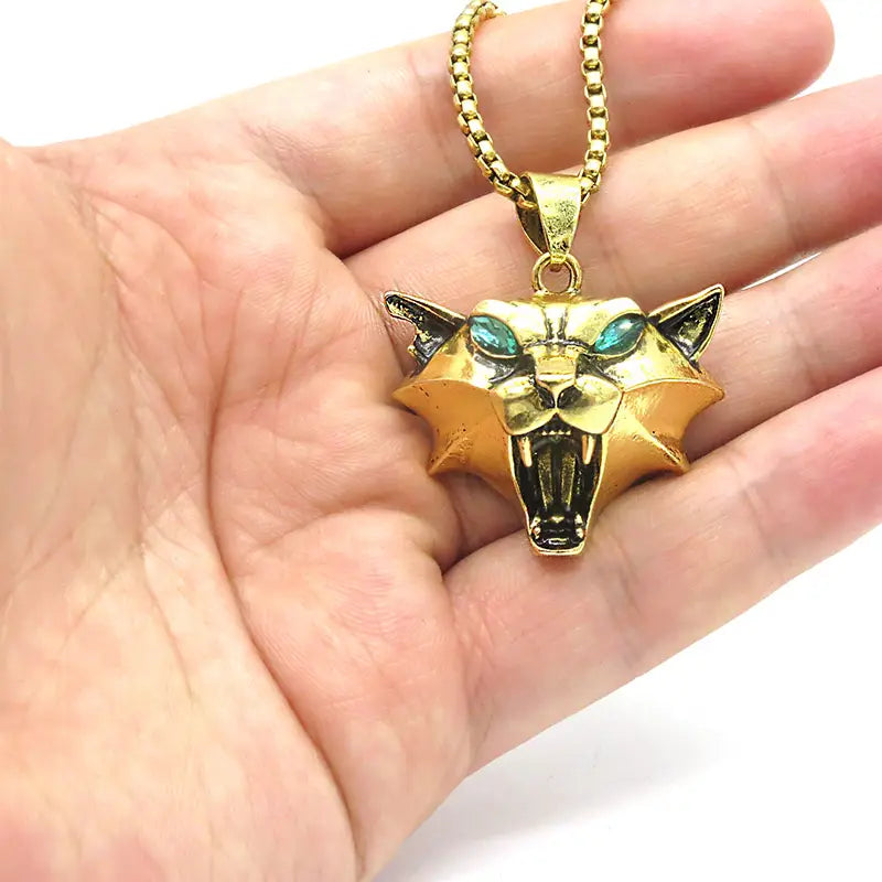 Gold-colored geometric wild game animal pendant chain necklace featuring a panther head with teal gemstone eyes and a textured metallic finish.