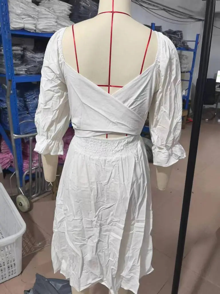 white cotton v-neck lantern sleeve reversible midi dress shown from the back with puffed sleeves and a cross-back design