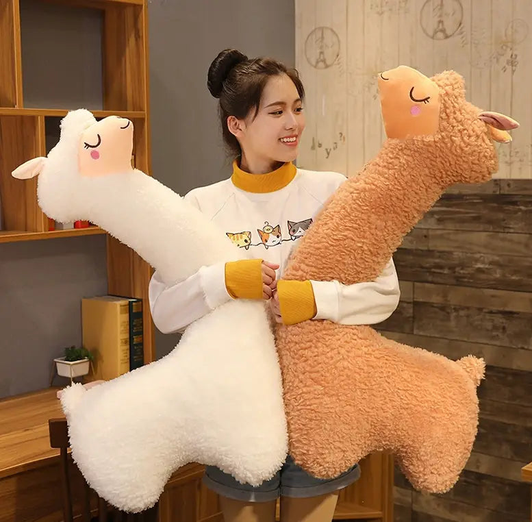 A plush long-necked alpaca stuffed toy pillow in white with closed eyes and pink cheek blush measuring 75cm.