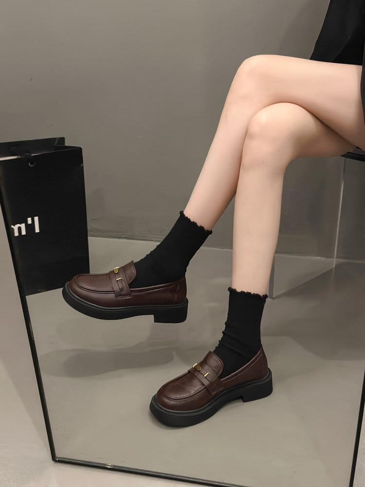 Brown leather loafers with a chunky black sole and gold buckle detail.