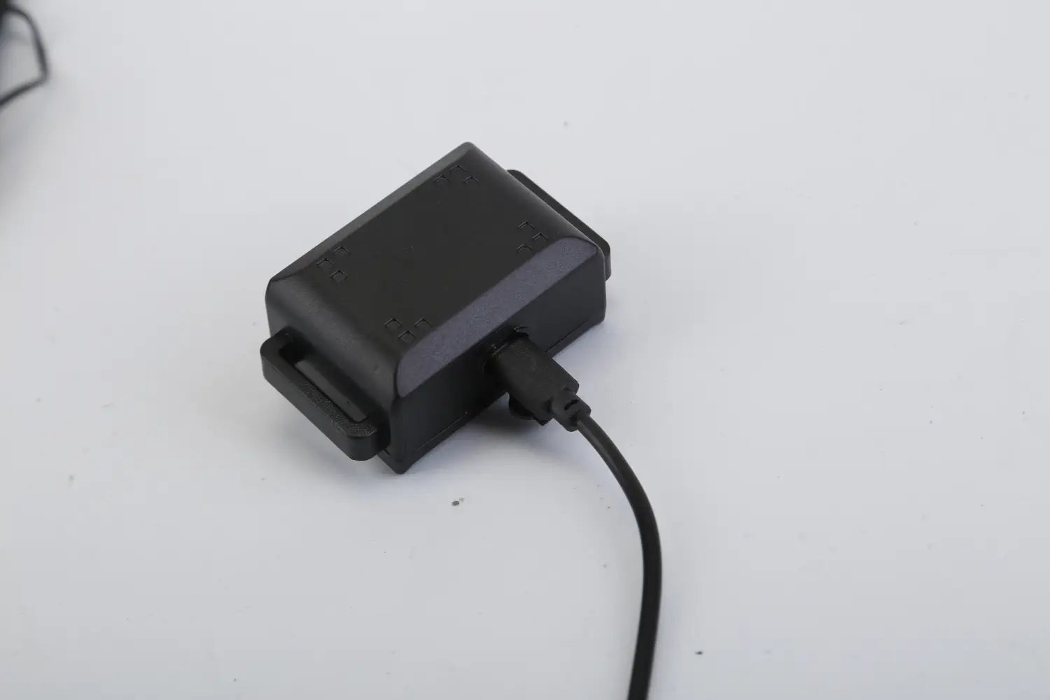 Black rectangular dog training collar device with usb cable connected to the side showing the back of the waterproof shock system.