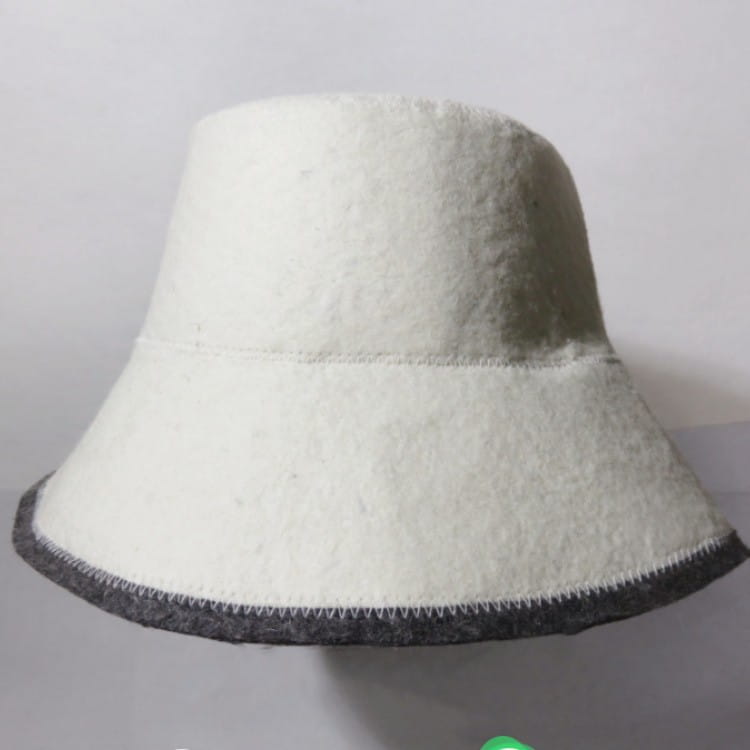 Eine weiße Woll- Saunahutfell-Haarkappe im Bucket-Hut-Stil mit dunkelgrauem, weiß gestepptem Zierband entlang der Kopfrandkante und der Nähtlinie am Oberkopf zur Wärmedämmung.