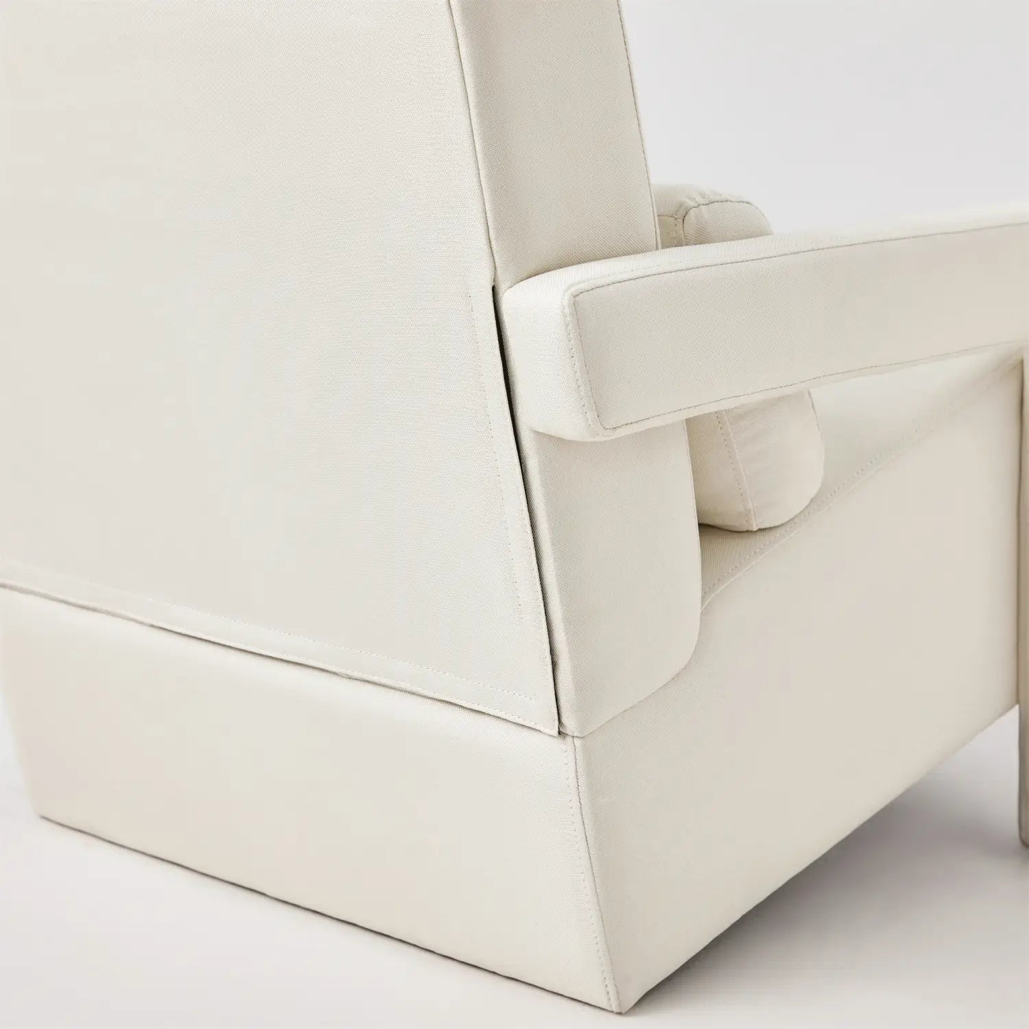 Cream-colored leather modern linen accent chair with pillow featuring clean lines and minimalist design for a beige living room.