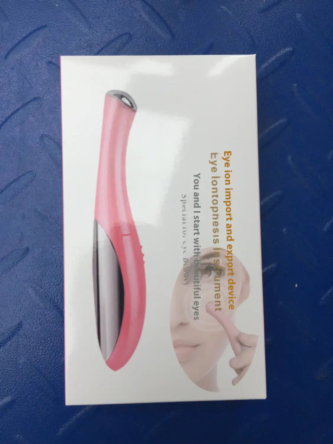 Pink and silver eye ion import and export device packaged as an eye massager for wrinkle and dark circle removal.