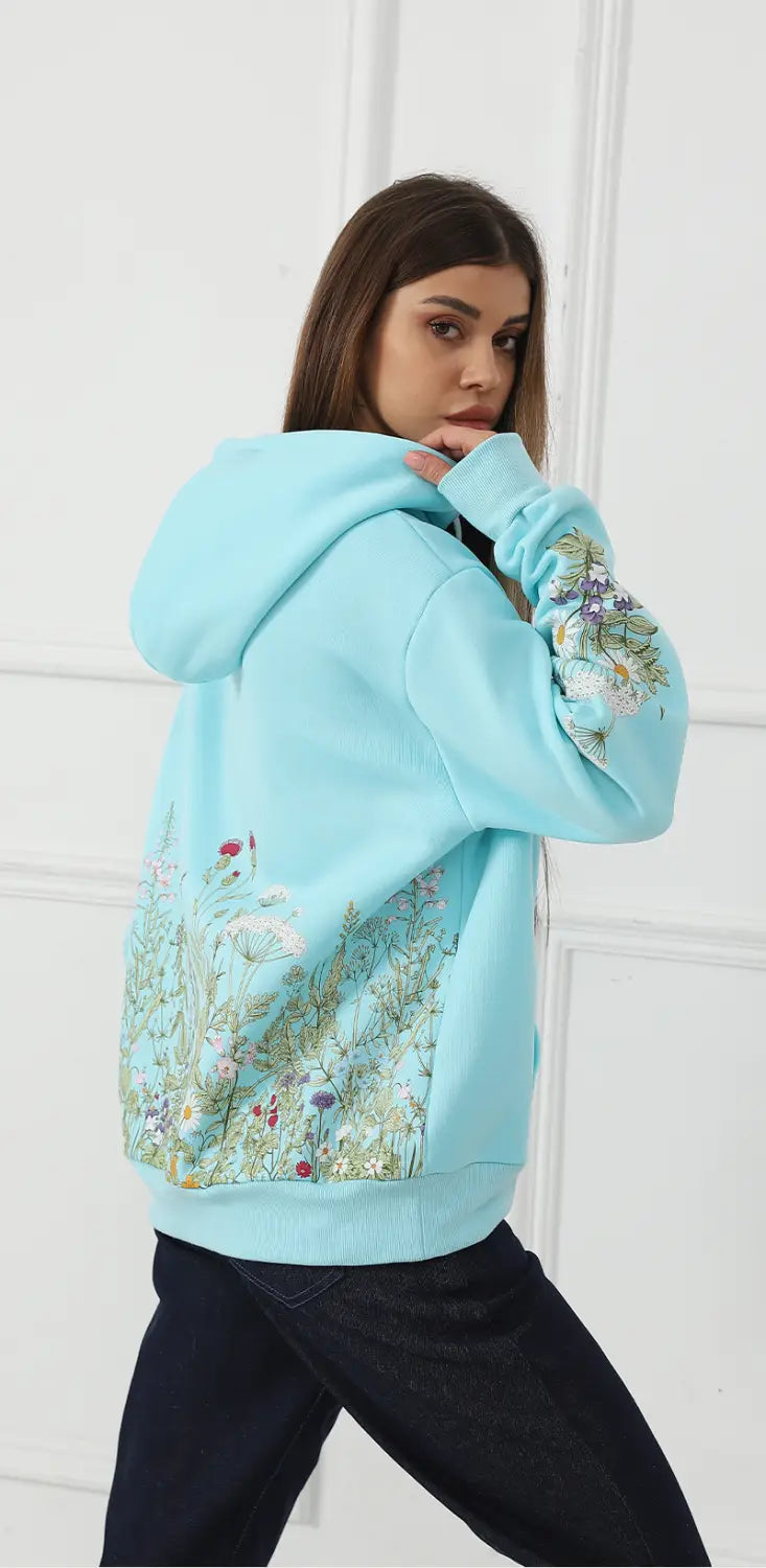 Light blue women’s long sleeve hoodie featuring intricate floral embroidery in soft pastel tones along the sleeves and back side.