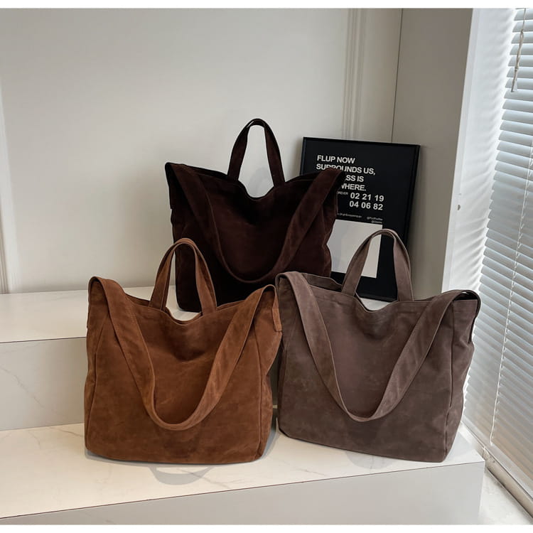 Three suede tote bags in earthy brown, tan, and dark chocolate tones made of corduroy displayed on a white surface.