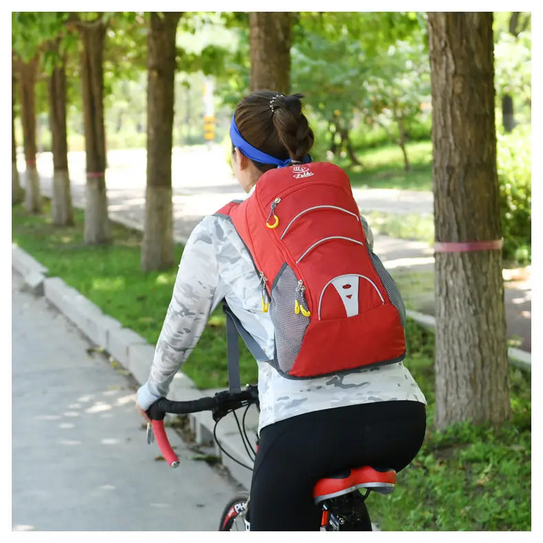 A red and gray hydration backpack with yellow zipper pulls shown from the back side, designed as a lightweight outdoor cycling bag for hikers.