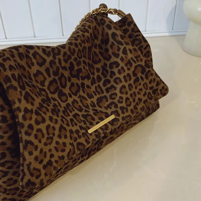 Leopard print crossbody bag in brown and black suede with a gold-tone chain strap.
