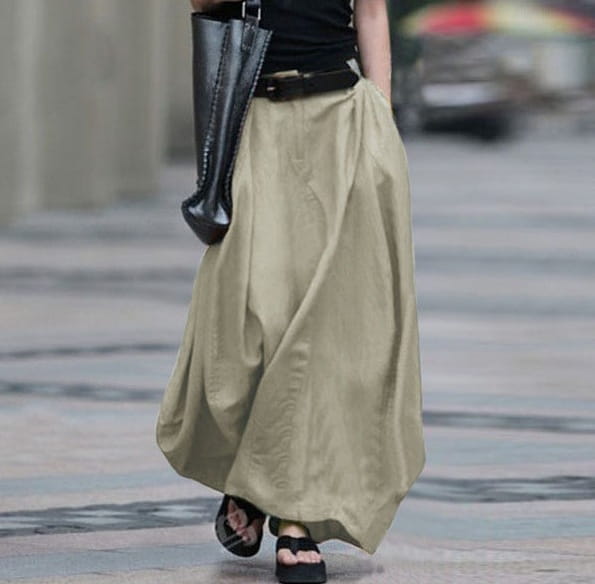 Une jupe longue maxi en coton vert olive fluide, avec une coupe décontractée et des plis subtils, conçue comme une jupe longue en satin taille haute.