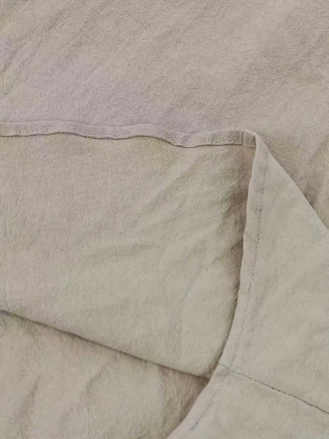Beige Leinen-Decke mit einer weichen, strukturierten Webart und sauber vernähten Kanten neben einem Herren-Cotton-Leinenhemd mit Kordelzug.