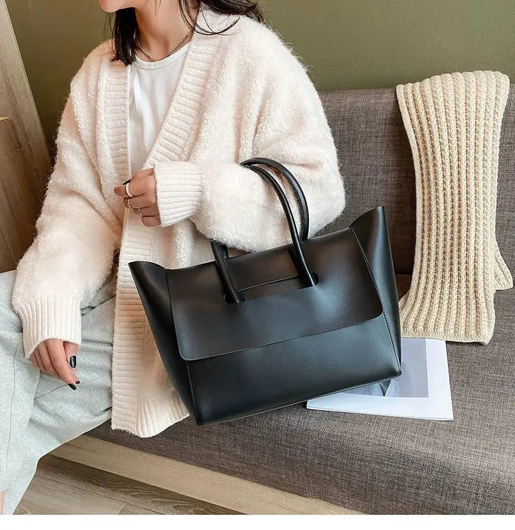 Black leather vintage structured tote bag with top handles designed for elegant everyday use.
