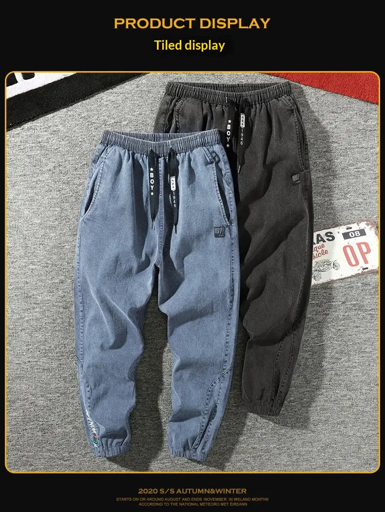 Men’s relaxed fit denim joggers in blue with a drawstring waist and a small embroidered logo on the thigh.