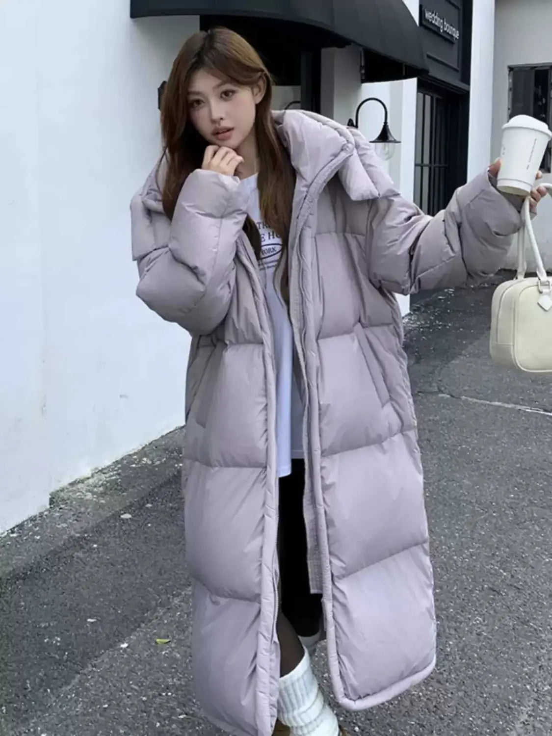 Un long manteau duveteux gris avec col haut et design matelassé, conçu pour les femmes en tant que manteau d’hiver matelassé et ouaté.