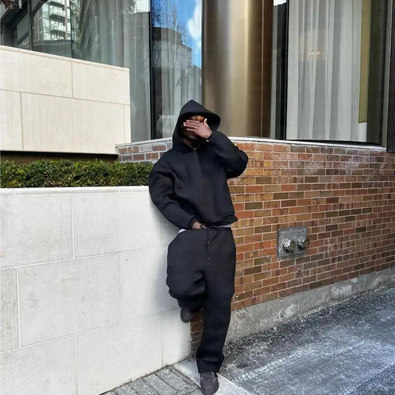 Sweat-shirt à capuche noir à coupe ample avec taille à cordon, issu de l’ensemble oversize unisexe streetwear comprenant un sweat à capuche et un pantalon de survêtement.
