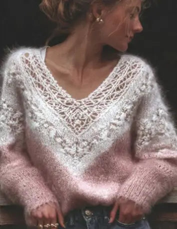 Un suéter de punto tejido en degradado suave de color rosa con textura, que presenta detalles de encaje intrincados a lo largo del escote en V y los hombros.