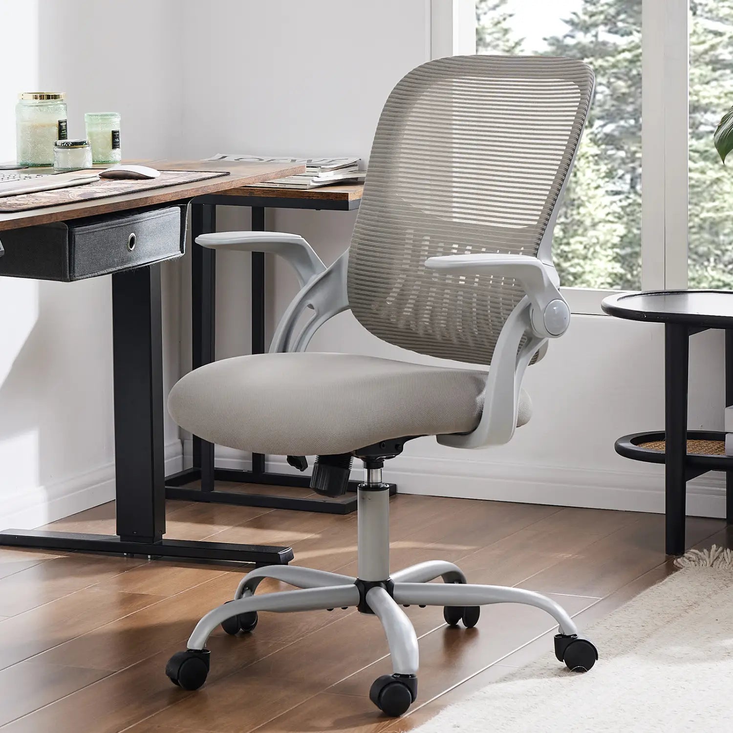 Chaise de dessin ergonomique à hauteur élevée, tabouret pour bureau debout, avec dossier en maille grise réglable avec accoudoirs, assise rembourrée, piètement métallique élégant et roues à roulettes noires, illustrée depuis l’arrière.