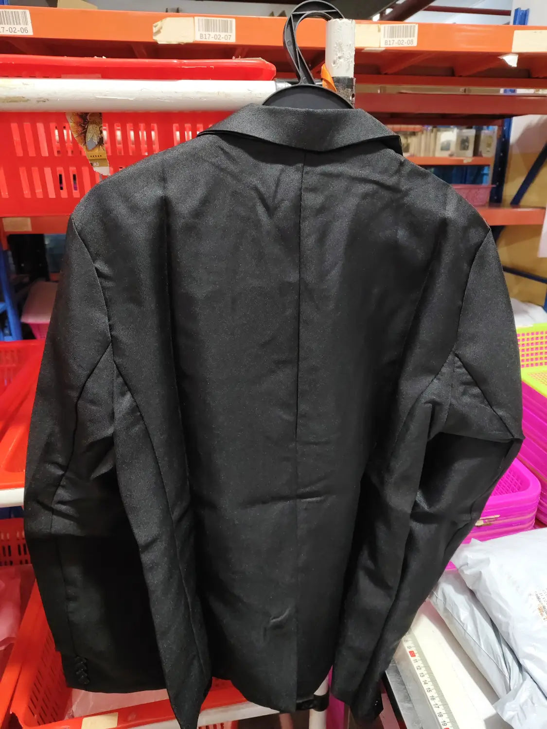 Veste de blazer décontractée à simple boutonnage bleu marine pour homme avec un dos structuré et un col à encolure crantée, suspendue sur un cintre dans un contexte de magasin de vente au détail