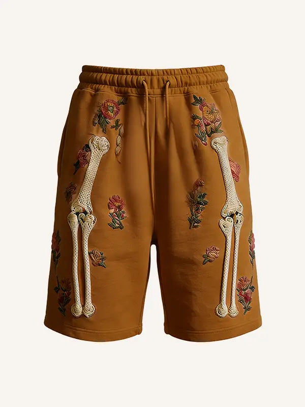 Tan polyester skeleton floral sweat shorts featuring embroidered floral patterns and prominent white knitted bone designs on the sides