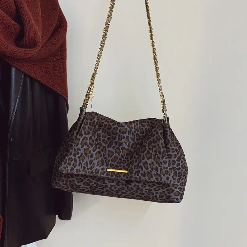 A stylish leopard print crossbody bag featuring a gold chain strap and matching metallic clasp.