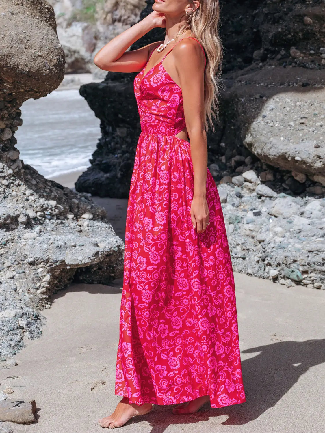 A vibrant pink floral knotted v neck maxi dress with thin spaghetti straps and a fitted waist.