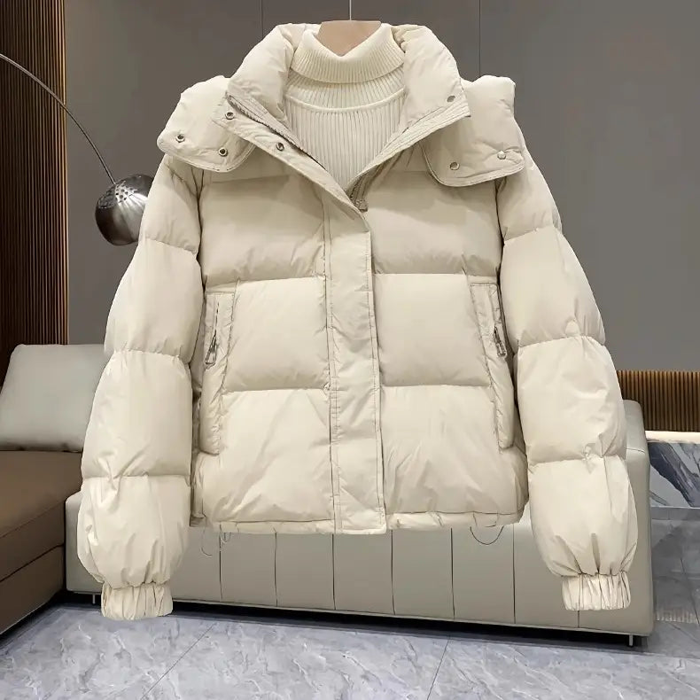 Cream-colored women puffer jacket hooded quilted winter coat made of down with a detachable hood and ribbed cuffs.