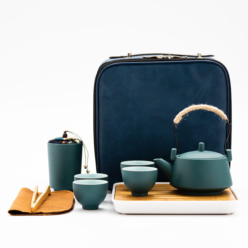 ceramic travel tea set with bamboo tray and case featuring a teal ceramic tea set with woven handle and matching cups on a bamboo tray beside a navy blue carrying case
