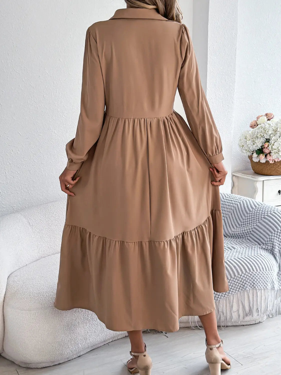 A soft beige women’s long sleeve tiered button down midi dress with a collar and elasticized waist.